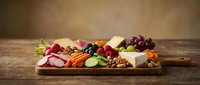 Gourmet cheese and charcuterie board with assorted meats, fruits, nuts and crackers on rustic wooden table for entertaining and appetizer presentation.