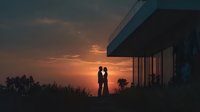 Romantic couple silhouette embracing at sunset near modern house with dramatic orange sky and scenic landscape view for love and relationship concepts.