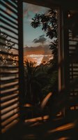 Tropical sunset view through wooden window blinds, palm trees silhouetted against orange sky and clouds, creating moody vacation atmosphere for travel content.
