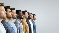 Diverse group of young men standing in profile line showing unity and teamwork in modern casual clothing against neutral background.