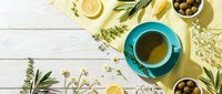 Herbal tea cup with fresh herbs, lemon slices and olives on rustic wooden background. Natural wellness and healthy lifestyle flat lay composition.