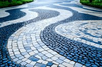 Decorative wavy pattern of black and white cobblestone pavement creating flowing curves and movement in urban landscape design, traditional Portuguese style.
