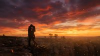 Couple embracing on hilltop at sunset with dramatic orange and red sky, cityscape below, romantic moment during golden hour for wedding and engagement projects.