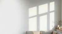 Sunlight streaming through large window panes casts geometric shadows on white wall above neutral sofa, creating minimalist interior design aesthetic for home decor and architectural visualization.