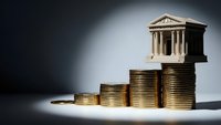 Financial growth concept with classical bank building on ascending coin stacks representing investment success and economic prosperity.