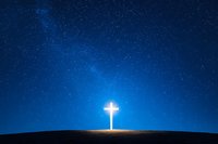 Glowing Christian cross on hill silhouette against dark blue starry night sky. Bright light emanating from religious symbol creates spiritual atmosphere.