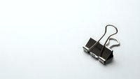 Black metal binder clip on white background for office organization and document management needs.