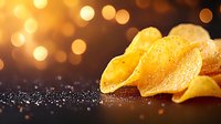 Crispy golden potato chips with salt crystals on dark surface with warm bokeh lights creating festive snack food atmosphere for advertising and packaging.