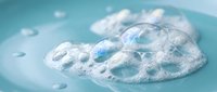 Clear contact lens floating in refreshing blue water with bubbles for vision care and eye health concepts.