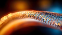 Macro shot of metallic mesh or wire structure with orange and blue bokeh lights creating futuristic technological atmosphere. Abstract background for tech designs.