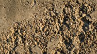 Rough textured brown soil surface with scattered clumps and granules creating natural earth pattern for agricultural and gardening backgrounds.