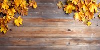 Rustic wooden background with vibrant yellow autumn maple leaves arranged along the edges, creating natural fall border decoration.