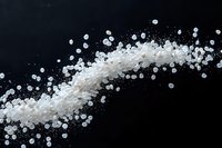 White salt crystals scattered in dynamic motion against black background, creating dramatic contrast and flowing pattern for culinary and artistic designs.