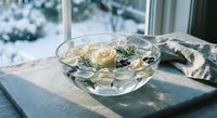 White roses floating in glass bowl with pine branches on windowsill creating elegant winter home decor arrangement for seasonal interior design styling.