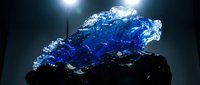 Stunning blue crystal mineral specimen with translucent formations and dramatic lighting effects on dark background for geology education and decorative purposes.