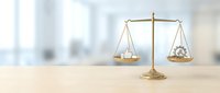Golden brass scales of justice balancing dollar sign and gear symbol on wooden desk representing business law, legal finance, and corporate justice concepts.