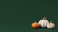 Decorative pumpkins in orange and white with gold stems arranged on deep green background, suitable for fall, autumn, and seasonal design projects.