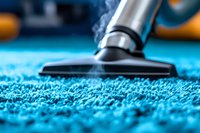 Close-up view of vacuum cleaner brush head on bright turquoise carpet with visible fibers and dust particles, demonstrating professional cleaning service in action.