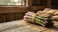Fresh green asparagus spears bundled with twine on rustic wooden table in natural sunlight for healthy cooking and farm-to-table cuisine preparation.