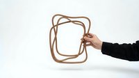 Hand holding abstract wooden frame sculpture with curved organic shapes against white background for modern interior design and artistic decoration.