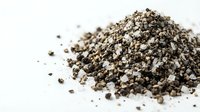 Pile of crushed black pepper spice granules scattered on white background for culinary cooking and seasoning applications.