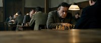 Middle-aged Caucasian man concentrating on chess game in dimly lit room with warm lighting. Strategic thinking and mental focus concept for business.