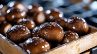 Fresh brown mushrooms sprinkled with coarse salt crystals on wooden surface, macro food photography with selective focus and bokeh light effects.
