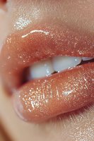 Close-up of glossy coral lips with sparkly glitter makeup effect showing white teeth, suitable for beauty and cosmetic advertising campaigns and editorial use.