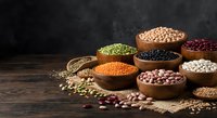 Assorted legumes and grains in wooden bowls on rustic table. Colorful variety of lentils, beans, chickpeas and seeds for healthy cooking and nutrition.