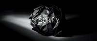 Crumpled black paper ball with the word Sorry written on it, dramatic dark moody lighting, concept of regret, apology, and mistake.