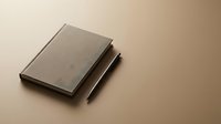 Minimalist brown notebook with matching pen on neutral beige background for branding, stationery design, corporate identity and business materials.