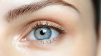 Close up macro shot of bright blue eye with long eyelashes and perfectly groomed eyebrow showing natural beauty and health care concept.