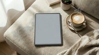 Digital tablet with blank screen on cozy beige sofa with coffee cup and blanket for morning relaxation and technology lifestyle concept.