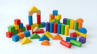 Colorful wooden building blocks set with various geometric shapes including cubes, cylinders, triangles and arches isolated on white background for educational play.