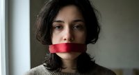 Young woman with dark hair and red tape over mouth symbolizing censorship, silence, and freedom of speech restrictions in modern society.