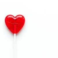 Red heart-shaped lollipop candy on white stick isolated on white background for Valentine's Day romance sweet treat confectionery design.