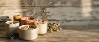 Scented candles with dried flowers and herbs arranged on rustic wooden surface, creating warm ambiance for home decor and relaxation.
