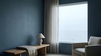 Modern minimalist bedroom with blue-grey walls, wooden nightstand with lamp, flowing white curtains, and contemporary furniture overlooking serene landscape view.