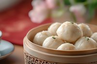 Fresh steamed dumplings in bamboo steamer basket with herbs, traditional Asian cuisine ready for serving in restaurant or home kitchen setting.