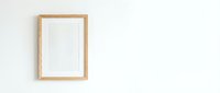 Minimalist wooden frame with white mat hanging on clean white wall, modern interior design element for home decor and gallery wall displays.