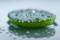 Fresh lime slice covered with water drops on reflective surface, macro photography showing detailed texture and natural freshness in green and silver tones.