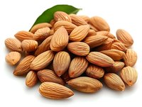 Fresh raw almonds with green leaf on white background, macro shot showing detailed texture and natural pattern of nuts suitable for healthy eating concepts.