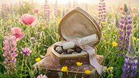 Heart-shaped box with chocolates and love note in a blooming wildflower meadow, romantic gift concept for Valentine's Day.