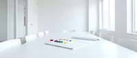 Modern white conference room with oval table, chairs and colorful markers for business meetings and corporate presentations.
