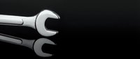 Chrome wrench tool on black surface with reflection for automotive repair and maintenance work projects.