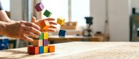 Adult hands building colorful wooden block tower on desk, creative problem solving and strategic planning concept for business development.