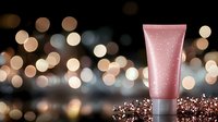 Pink glittery cosmetic tube on dark background with bokeh lights and sparkles, luxury beauty product photography for skincare and cosmetics marketing.