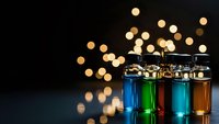Laboratory test tubes with colorful chemical solutions against bokeh lights background for scientific research and medical analysis projects.