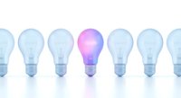 Row of light bulbs with one glowing purple bulb standing out among transparent ones, representing innovation, creativity and unique ideas for business concepts.