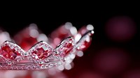Sparkling crystal crown with delicate details in pink and red tones against dark background, creating romantic and royal atmosphere. Luxury accessory for princess theme.